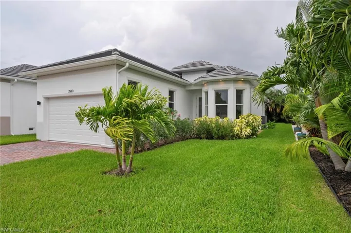 View of property exterior with a yard, stucco siding, a garage, and decorative driveway