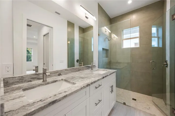 Full bathroom with a stall shower, double vanity, and recessed lighting