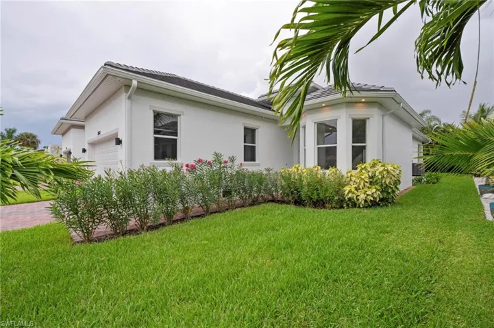 View of property exterior featuring stucco siding, a lawn, a garage, and decorative driveway