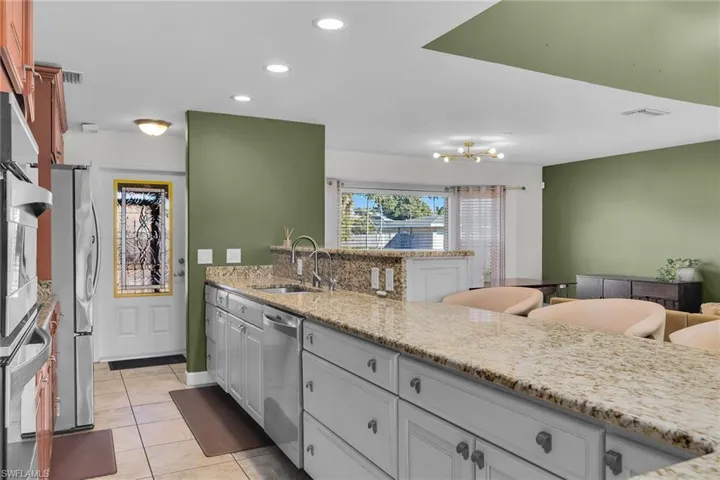 Kitchen featuring light stone countertops, recessed lighting, a peninsula, light tile patterned floors, and stainless steel appliances