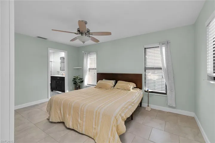 Bedroom featuring a ceiling fan, connected bathroom, and light tile patterned floors