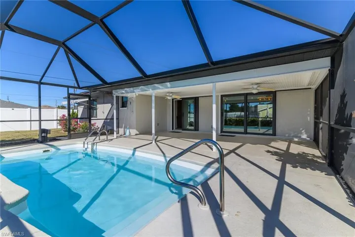 View of swimming pool with a sunroom, glass enclosure, and a patio