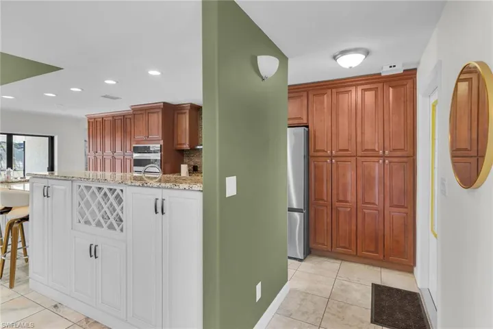 Kitchen with light stone counters, light tile patterned floors, stainless steel appliances, recessed lighting, and a kitchen bar