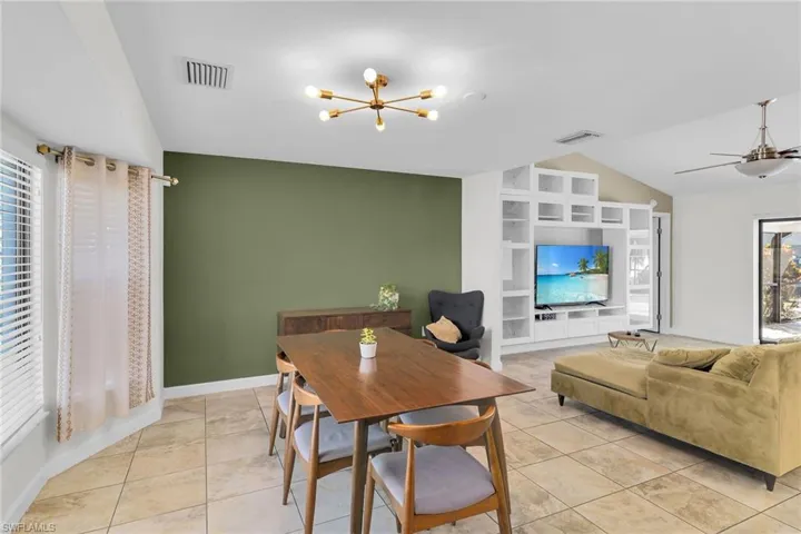 Dining room with plenty of natural light, a chandelier, vaulted ceiling, light tile patterned flooring, and built in shelves