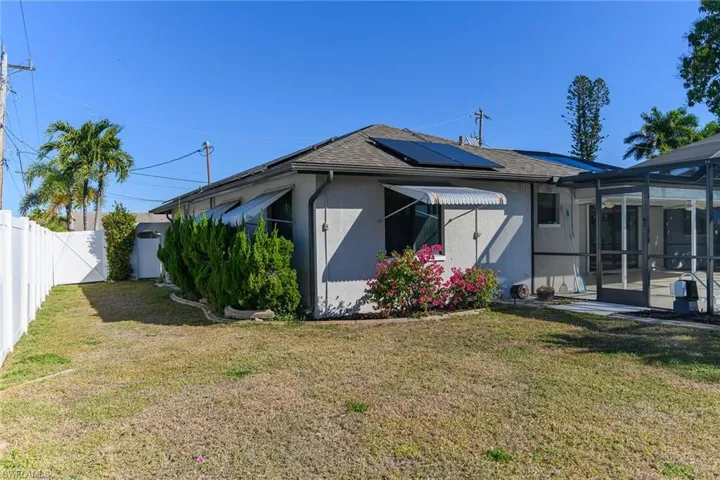 Back of property featuring a sunroom, glass enclosure, stucco siding, a fenced backyard, and a shingled roof