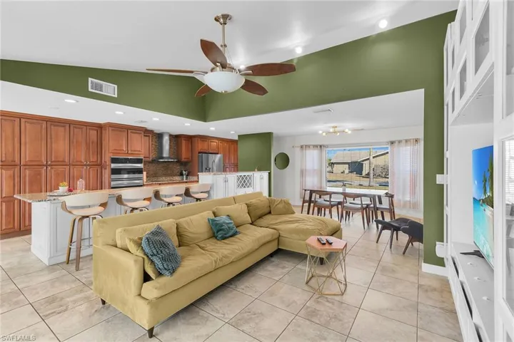 Living room featuring recessed lighting, a ceiling fan, vaulted ceiling, light tile patterned floors, and a chandelier