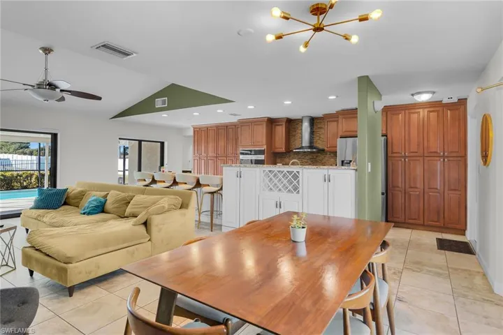 Dining space with a chandelier, light tile patterned floors, recessed lighting, ceiling fan, and lofted ceiling