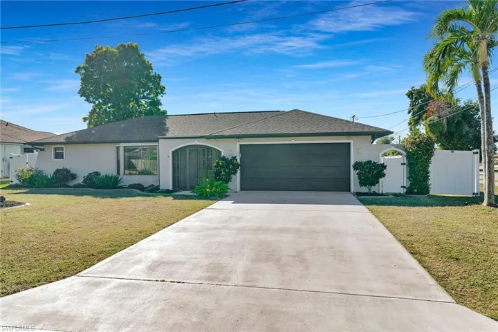 Single story home featuring stucco siding, concrete driveway, a front lawn, and a gate