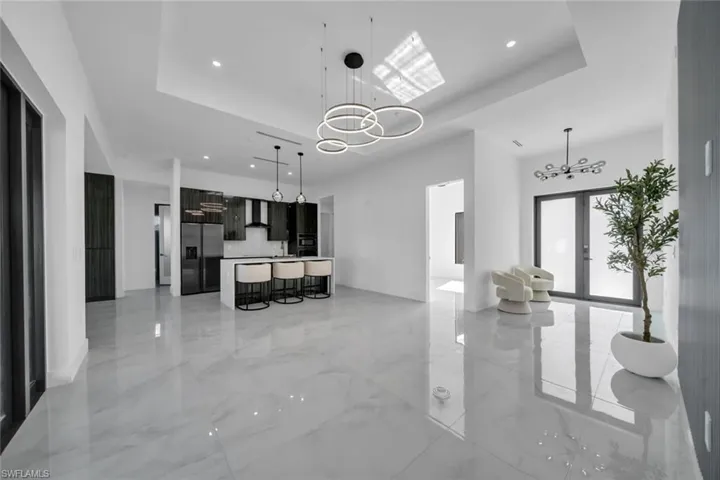 Kitchen featuring light countertops, recessed lighting, a kitchen bar, refrigerator with ice dispenser, and a chandelier
