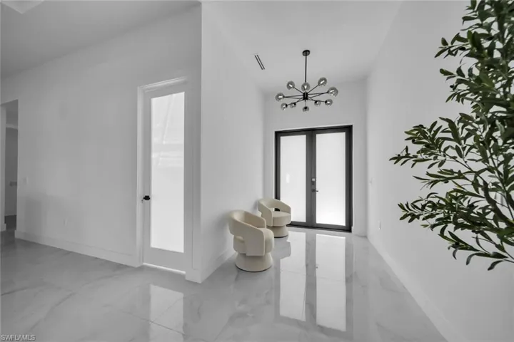 Foyer entrance featuring french doors, a chandelier, and light marble finish flooring
