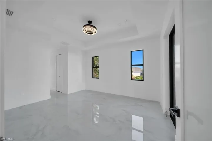 Empty room with a raised ceiling and light marble finish flooring