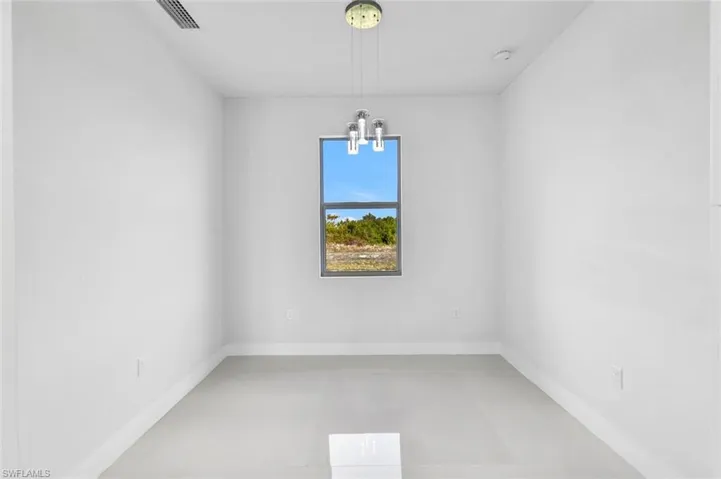 Empty room with a chandelier and finished concrete flooring