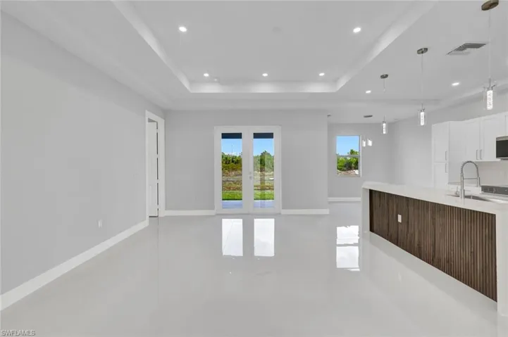 Unfurnished living room with recessed lighting, a raised ceiling, and french doors