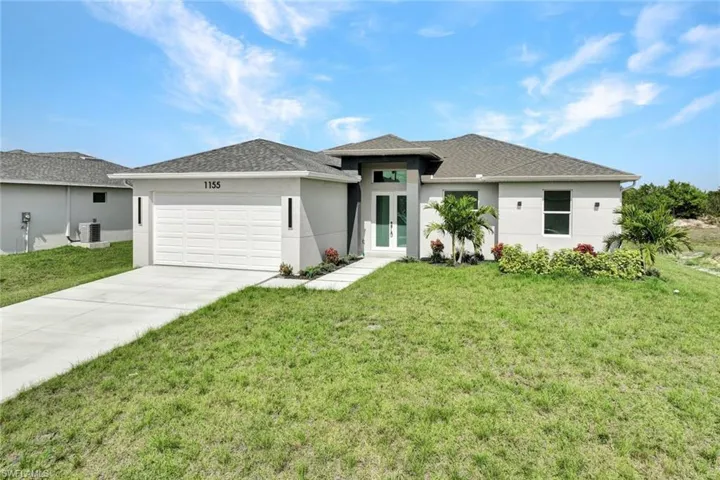Prairie-style home featuring stucco siding, a garage, a front yard, and concrete driveway