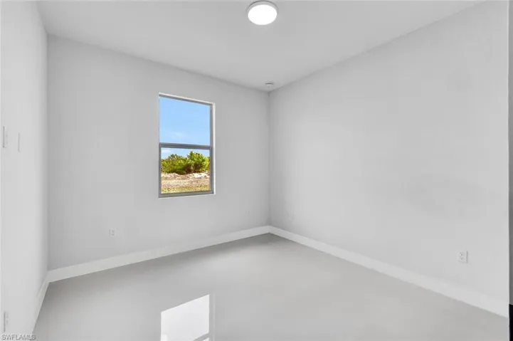 Unfurnished room featuring finished concrete floors and baseboards