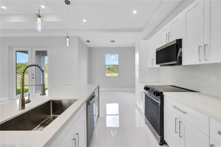 Kitchen featuring range with electric cooktop, recessed lighting, a tray ceiling, white cabinetry, and pendant lighting