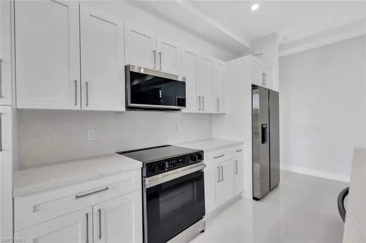Kitchen with stainless steel appliances, white cabinets, tasteful backsplash, recessed lighting, and light stone countertops