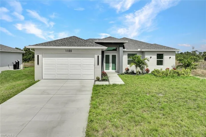 View of front of property featuring a garage, stucco siding, french doors, driveway, and a front lawn