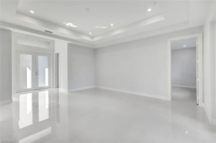 Spare room featuring a tray ceiling, french doors, finished concrete floors, and recessed lighting