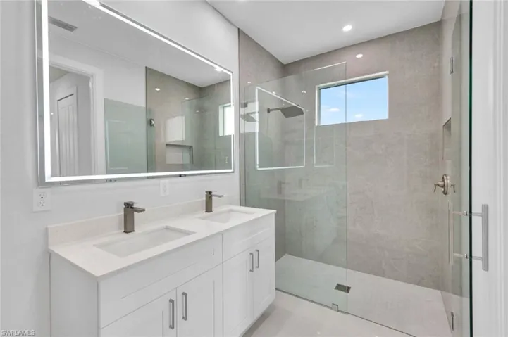 Bathroom with a shower stall, double vanity, and recessed lighting