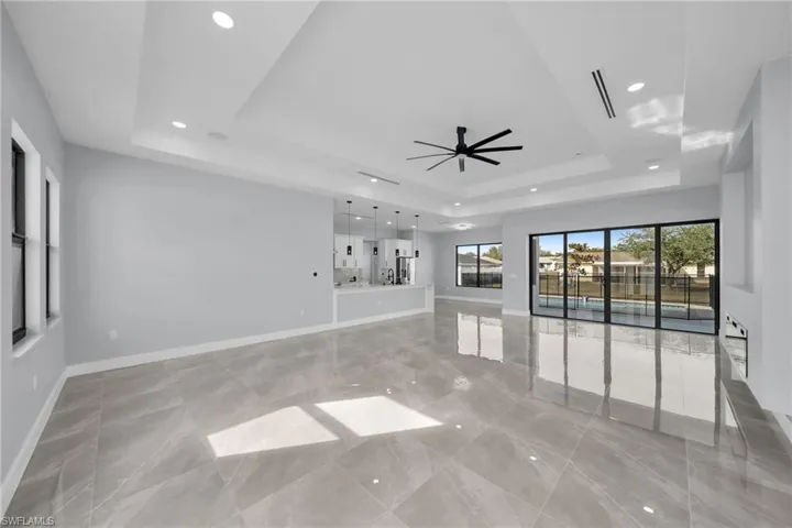 Unfurnished living room featuring ceiling fan and a tray ceiling