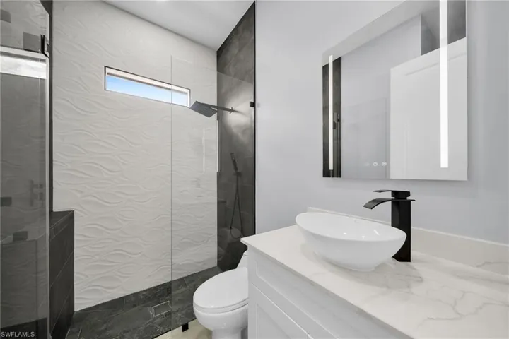 Bathroom with toilet, vanity, and a tile shower