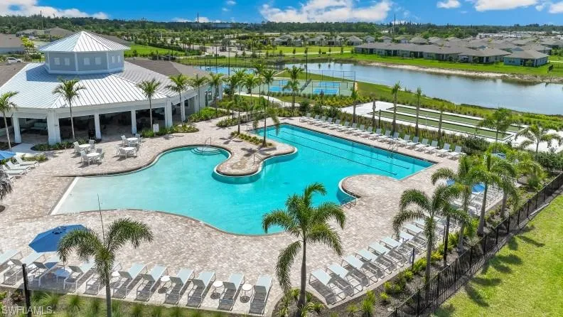 Expansive outdoor area featuring a swimming pool, lounge chairs, a shaded seating area, and a building with a corrugated metal roof