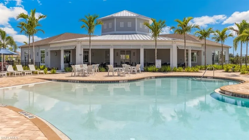 The property features an outdoor swimming pool, surrounded by a paved patio area with lush palm trees