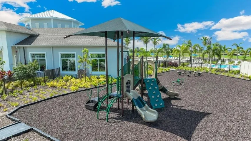 This property features a recreational area with a multi-component playground structure, complete with slides and climbing elements, situated on a dark-colored soft surface