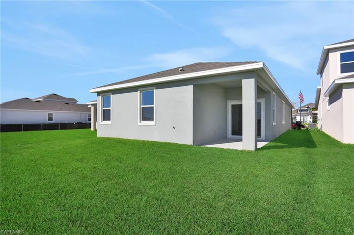Back of house with stucco siding, a patio area, and a shingled roof