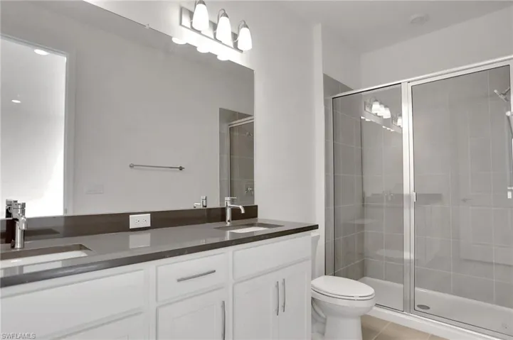 Full bathroom with double vanity, a stall shower, and light tile patterned floors