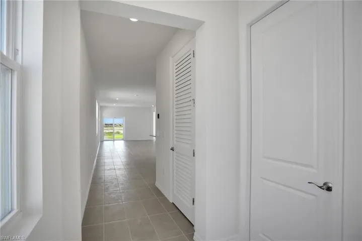 Hall with light tile patterned flooring and recessed lighting