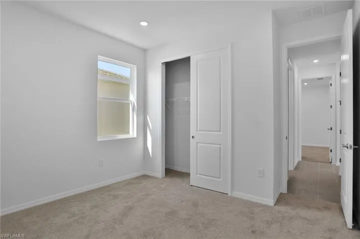 Unfurnished bedroom with light colored carpet, a closet, and recessed lighting