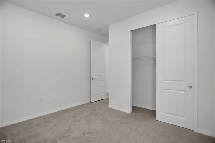 Unfurnished bedroom with light carpet, a closet, and recessed lighting