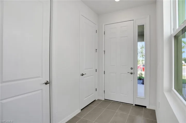 Foyer entrance with light tile patterned floors and recessed lighting