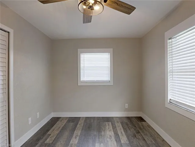Spare room with dark wood-type flooring, plenty of natural light, and a ceiling fan