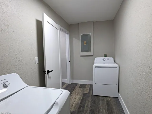 Laundry area with a textured wall, washer / clothes dryer, dark wood finished floors, and electric panel