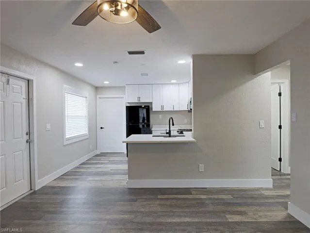 Kitchen featuring white cabinets, a textured wall, dark wood-style flooring, a peninsula, and recessed lighting