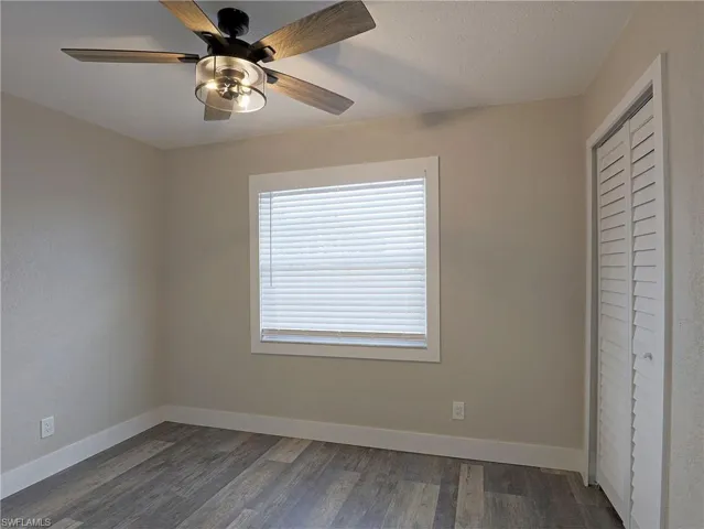 Unfurnished bedroom with dark wood-type flooring, a closet, and ceiling fan