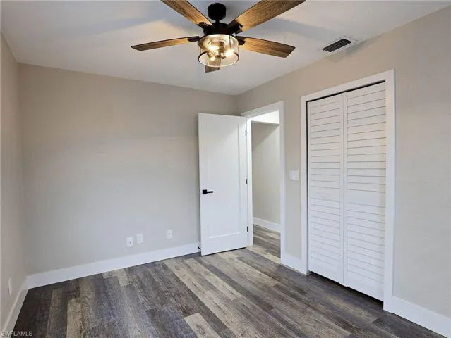 Unfurnished bedroom featuring dark wood-type flooring, ceiling fan, and a closet