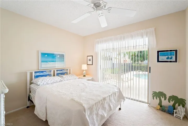 Carpeted bedroom featuring ceiling fan, a textured ceiling, and access to exterior
