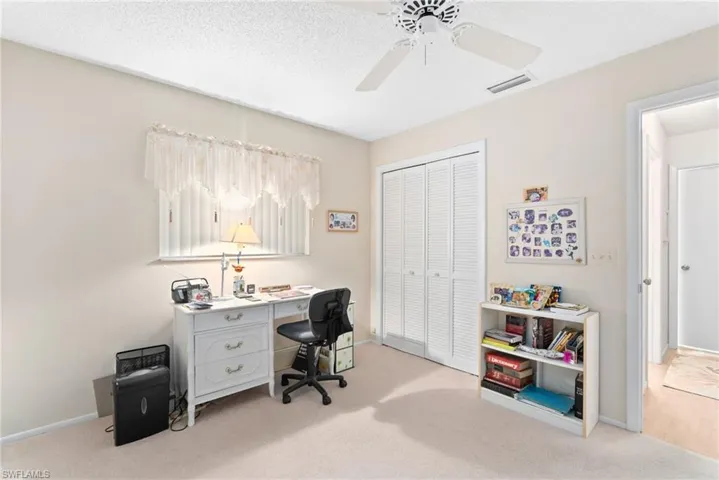 Home office featuring light carpet, ceiling fan, and a textured ceiling