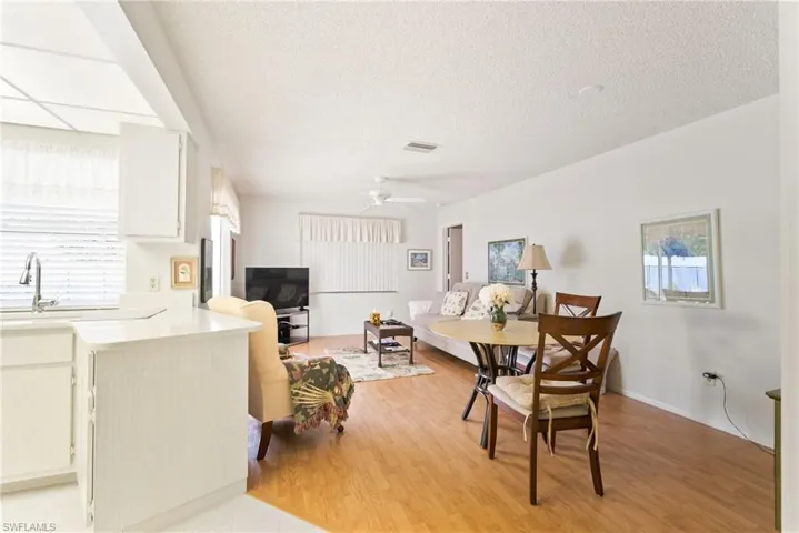 Dining area with a textured ceiling, ceiling fan, light hardwood / wood-style flooring, and sink