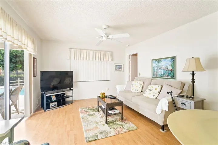 Living room featuring ceiling fan, hardwood / wood-style floors, and a textured ceiling