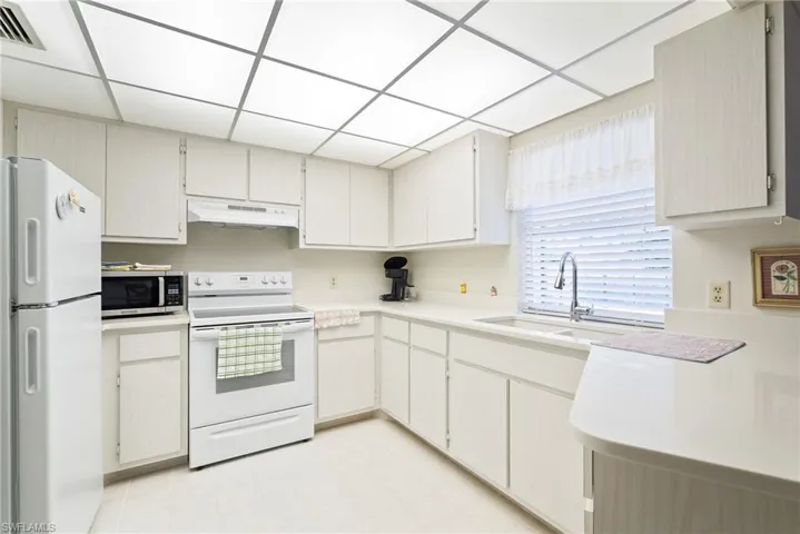 Kitchen with a paneled ceiling, sink, and white appliances