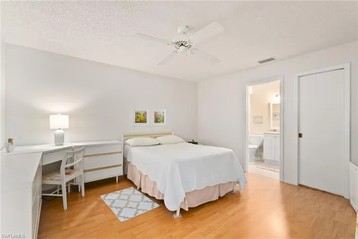 Bedroom featuring ceiling fan, a textured ceiling, ensuite bathroom, and light hardwood / wood-style floors