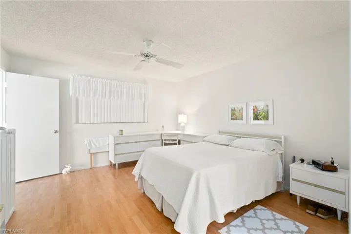 Bedroom with ceiling fan, a textured ceiling, and light wood-type flooring
