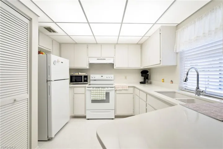 Kitchen featuring a paneled ceiling, sink, white appliances, and white cabinetry