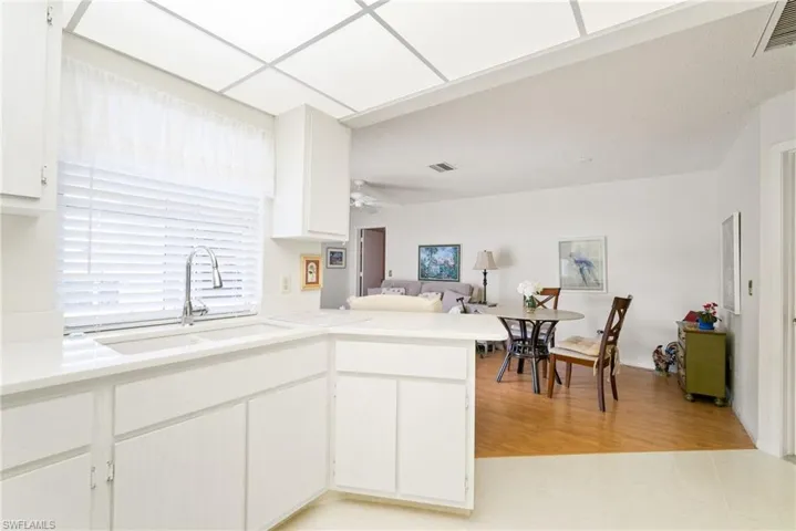 Kitchen featuring light hardwood / wood-style floors, white cabinets, kitchen peninsula, ceiling fan, and sink
