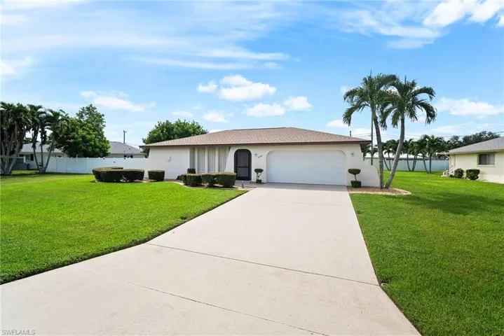 Single story home featuring a garage and a front lawn